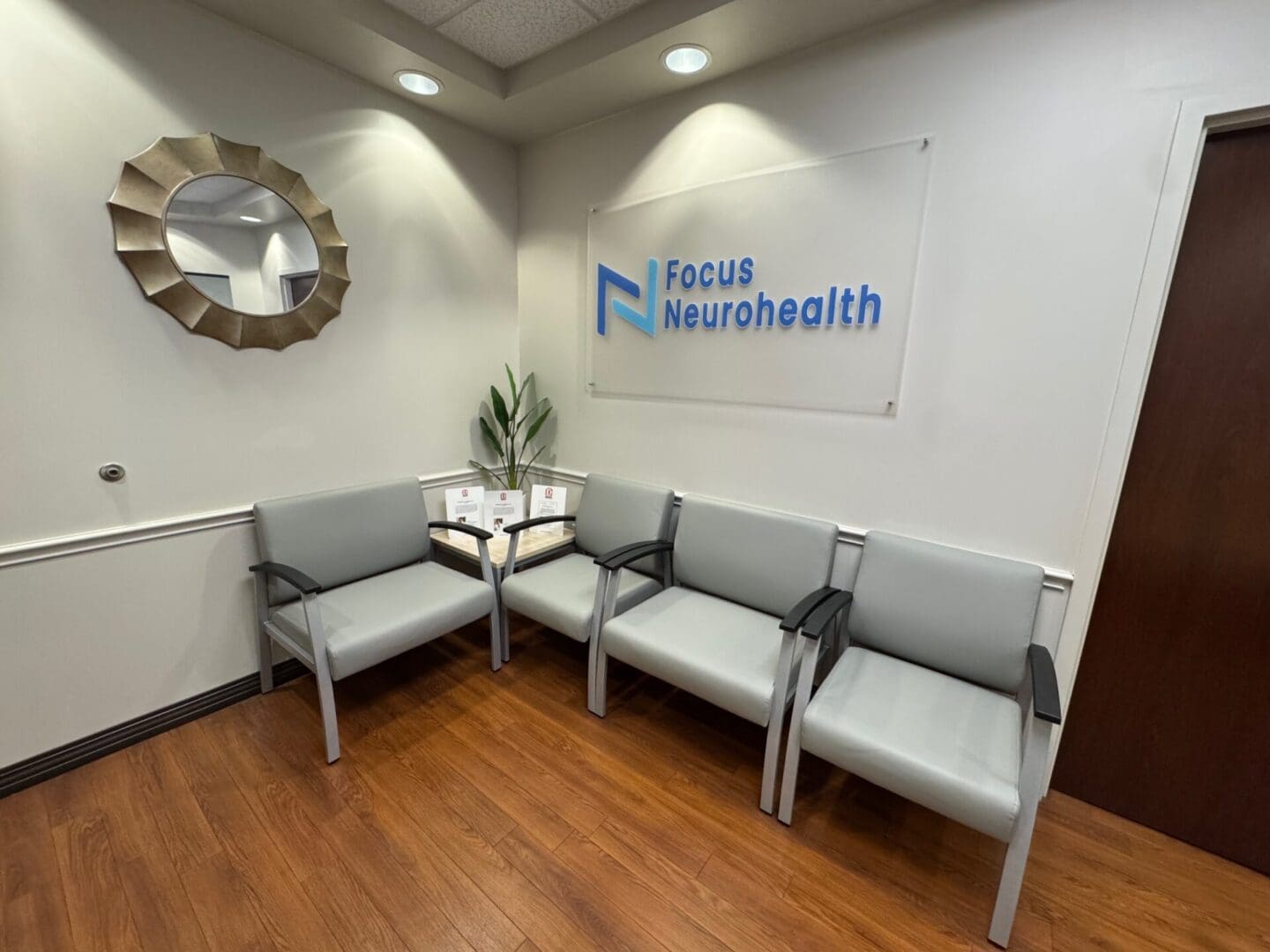 Medical office waiting room with gray chairs.