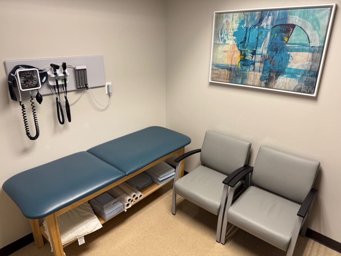 Medical examination room with chairs and artwork.